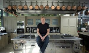 Gordon Ramsay sitter i ett lyxigt restaurangkök med kopparkastruller.