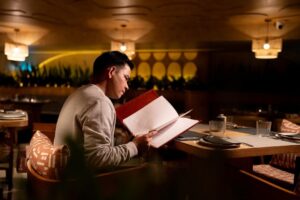 Gäst studerar en meny vid ett dukat bord i en varm restaurangmiljö