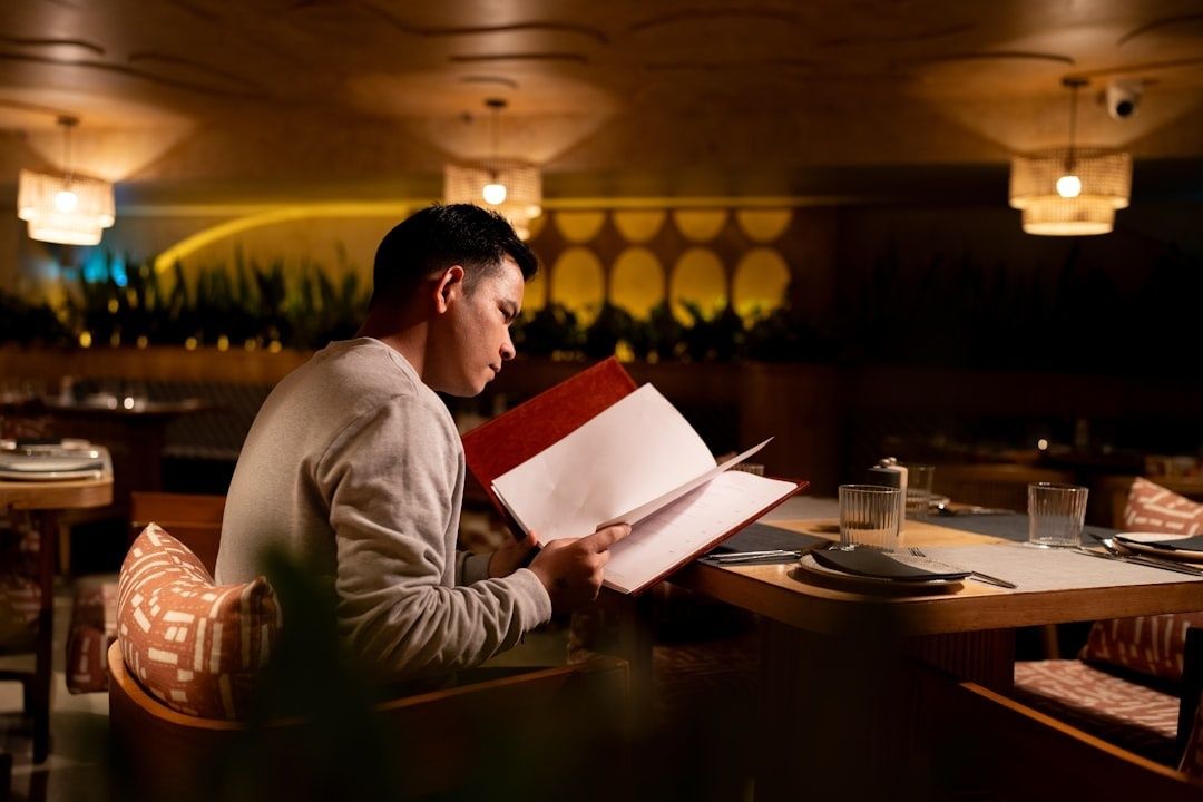 Gäst studerar en meny vid ett dukat bord i en varm restaurangmiljö
