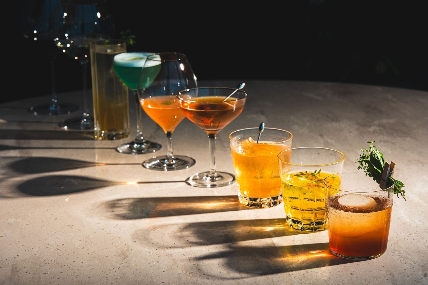 Färgstarka cocktails och drinkar i glas på en solbelyst bardisk
