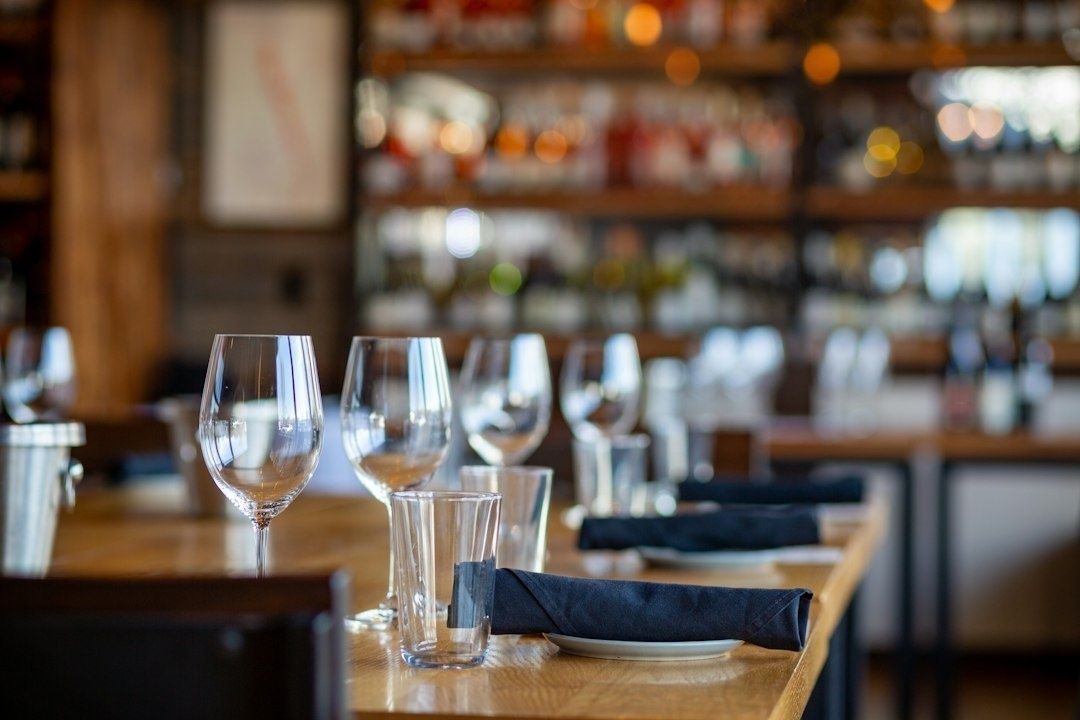 Restaurangbord med vinglas, vattenglas och mörka linneservetter